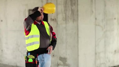 İnşaat alanında çalışan bir işçi. Proje alanında araçları olan sarı şapkalı ustabaşı