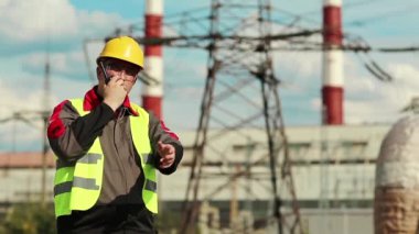 Isı santralindeki işçiler radyo istasyonu aracılığıyla iletişim kuruyor. Elektrik santralinde taşınabilir radyo vericisi olan güçlü bir adam.