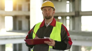 İnşaat alanındaki ustabaşı not alıyor. İnşaat alanında denetleyici personel. Proje alanında sarı şapkalı bir müfettiş. Mühendislik denetimi, inşaatçı notlar yazar