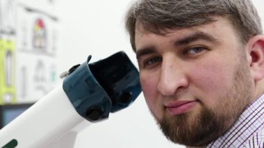 Göz hekimliği kliniğindeki hasta. Erkek, konaklama spazmı, amblyopia ve dürbün görme bozuklukları tedavisi için cihazın yanındaki kameraya bakar.