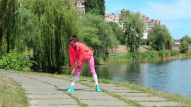 Kırmızı spor ceketli kız sabah egzersizleri yapıyor. Göl kenarında fiziksel egzersiz yapan bir kadın. Fiziksel aktivite kalorileri yakmaya yardımcı olur. Kız spora gider, kız spor yapar.