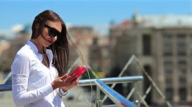 İş kadını akıllı telefon kullanır. Ukrayna 'nın Kiev şehrinde güneş gözlüklü, kırmızı cep telefonlu güzel bir kadın.