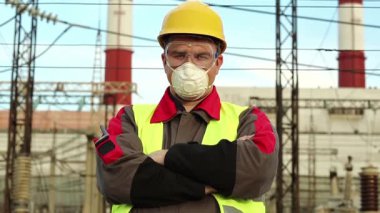 Sanayi bölgesinde baret, gözlük ve solunum cihazı takan tamirci. Kimyasal korumalı ısı elektrik santralinde çalışan işçiler kameraya bakıyor.