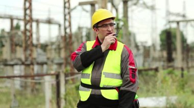 Isı santralindeki işçiler radyo istasyonuyla iletişim kuruyor. Elektrik santralinde taşınabilir radyo vericisi olan bir işçi.