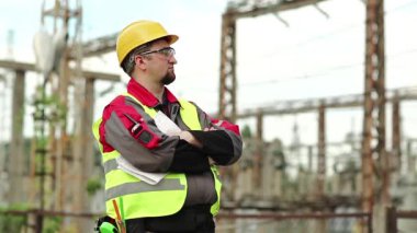 Gözlüklü işçiler ve elektrik santralinin kaskı önlerine bakıyor.