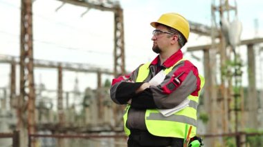 Elektrik santralinde çalışan bir işçi. Güç mühendisliği uzmanı gözlük ve baret konusunda ısı santralinde önümüze bakıyor.