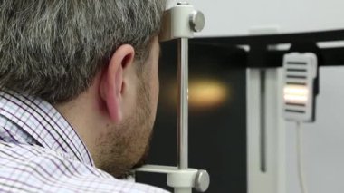 Dinamik fototerapi için bir cihaz. Optalmoloji kliniğindeki hasta, adam göz doktoru odasındaki dinamik fototerapi cihazına bakıyor, ışık tedavisi görüyor.