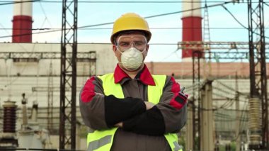 Sanayi bölgesinde baret, gözlük ve solunum cihazı takan tamirci. Kimyasal korumalı ısı elektrik santralinde çalışan işçiler kameraya bakıyor.