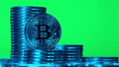 Bitcoin 'ler yeşil arka planda mavi ışıkta. Kripto para birimi Altın Bitcoin, BTC, Bit Coin, Blockchain teknolojisi, bitcoin madencilik konsepti, yeşil arka planda dönen makro mavi bitcoin vuruşu