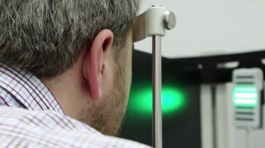 Dinamik fototerapi için bir cihaz. Optalmoloji kliniğindeki hasta, adam göz doktoru odasındaki dinamik fototerapi cihazına bakıyor, ışık tedavisi görüyor.