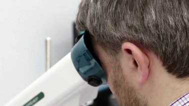 Erkek, konaklama spazmı, amblyopia ve dürbün görme bozukluklarının tedavisi için aparata bakar. Göz hekimliği kliniğindeki hasta.