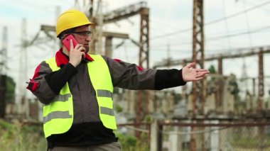 Elektrik santralindeki işçiler akıllı telefondan konuşur. Elektrik santralinde cep telefonuyla çalışan bir elektrik mühendisi.