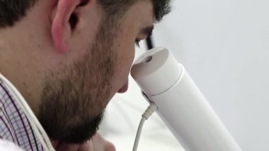 Göz hekimliği kliniğindeki hasta. Adam göz hekimliği ofisinde manyetik terapi için aletlerin içine bakıyor. Kafasında mıknatıslar var.