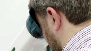 Göz hekimliği kliniğindeki hasta. Erkek, konaklama spazmı, amblyopia ve dürbün görme bozukluklarının tedavisi için aparata bakar.