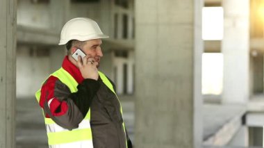 İnşaat alanında akıllı telefonu olan bir inşaatçı. İnşaat alanındaki inşaat konuşmalarında sarı sapkalı iş belgeleriyle çalışan ustabaşı. İnşaatçı proje sitesindeki cep telefonundan konuşuyor