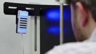 Dinamik fototerapi için bir cihaz. Göz hekimliği kliniğindeki hasta. İnsan göz doktoru odasındaki dinamik fototerapi cihazına bakar.