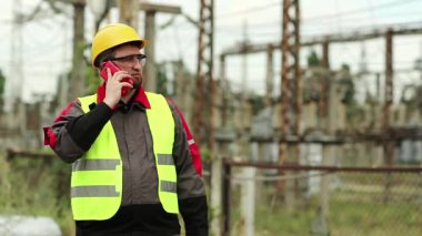 Elektrik santralinde cep telefonu ve taşınabilir radyo vericisi olan bir elektrik mühendisi. Elektrik santralindeki işçiler akıllı telefondan konuşuyor