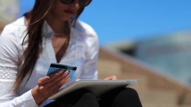 Tablet bilgisayarından kredi kartıyla online alışveriş yapan kadın, kredi kartıyla tablet bilgisayar yoluyla alışveriş yapıyor