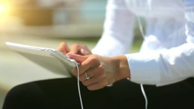Kız kapalı çekimde tablet bilgisayar kullanıyor. Fransız manikürlü kadın elleri tablet bilgisayarı, arka planda güzel bir güneş tutuyor.