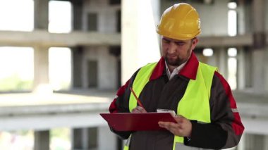 İnşaat müfettişi proje alanında çalışma belgeleriyle birlikte. Usta inşaatçı çalışma belgelerine notlar alır.