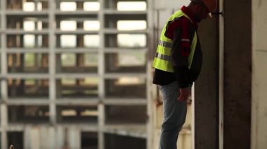 Stresli mimar inşaat sahasında duruyor ve kafasını beton duvara vuruyor, kendini kınıyor ve kendine işkence ediyor. İşçi kafasını duvara vuruyor.