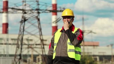 Isı santrali enerji mühendisliği uzmanı radyo istasyonu aracılığıyla iletişim kuruyor. Elektrik santralinde taşınabilir radyo vericisi olan güçlü bir adam.