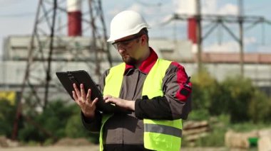 Elektrik santralinde kişisel bilgisayarda çalışan bir elektrik mühendisi. Isı elektrik santralinde çalışan, mühendislik denetimi altında çalışan bir işçi. Tablet bilgisayarlı fabrika işçisi