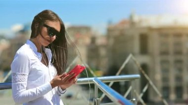 İş kadını akıllı telefon kullanır. Ukrayna 'nın Kiev şehrinde güneş gözlüklü, kırmızı cep telefonlu güzel bir kadın.