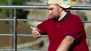 İş adamı akıllı telefonla çalışır. Kırmızı gömlekli adam akıllı telefon kullanıyor, elinde beyaz cep telefonu tutuyor.