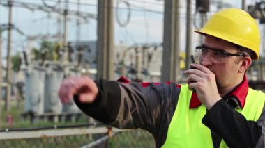 Isı santrali enerji mühendisliği uzmanı radyo istasyonu aracılığıyla iletişim kuruyor. Elektrik santralinde taşınabilir radyo vericisi olan güçlü bir adam.