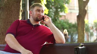 Adam akıllı telefondan konuşuyor. İşadamı kürsüde oturuyor ve akıllı telefon aracılığıyla iletişim kuruyor.