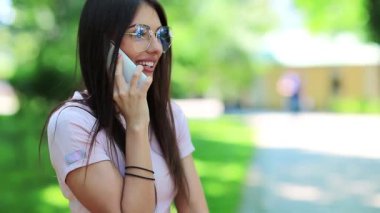 İş kadını cep telefonuyla konuşuyor. Gözlüklü güzel bir kız cep telefonuyla konuşuyor, beyaz akıllı telefonlu bir kadın.