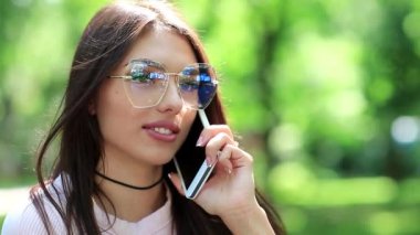 Gözlüklü güzel bir kız cep telefonuyla konuşuyor. Beyaz akıllı telefonlu bir kadın. İş kadını cep telefonuyla konuşuyor