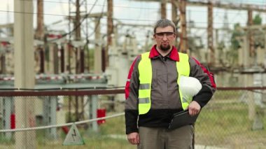 Elektrik santralinde çalışan bir işçi. Güç mühendisliği uzmanı gözlük ve baret uzmanı ısı santralinde kameraya bakıyor.