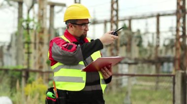 Elektrik santralinde taşınabilir radyo vericisi olan bir elektrikçi. Isı santrali enerji mühendisliği uzmanı radyo istasyonu aracılığıyla iletişim kuruyor.