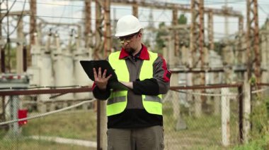 Elektrik santralinde bilgisayarı olan bir elektrikçi. Tablet bilgisayarı olan bir fabrika işçisi. Elektrik santralinde kasklı işçi, mühendislik denetimi.