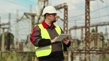 Güç istasyonunda tablet bilgisayarı olan bir Powerman. Elektrik santralindeki beyaz başlıklı işçi, mühendislik denetimi. Tablet bilgisayarlı fabrika işçisi