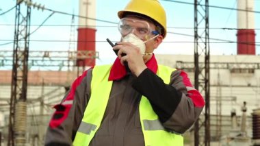 Gaz maskeli işçi radyo vericisiyle konuşuyor. Gaz maskesi, gözlükler ve ısı santralinin başlığı konusunda uzman olan elektrik mühendisi radyo istasyonu aracılığıyla iletişim kuruyor.