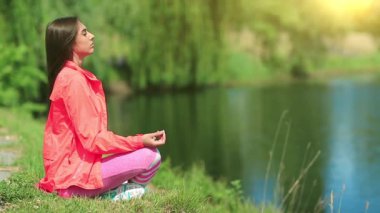 Güzel bir kadın gölün kenarında meditasyon yapar. Arka planda güzel bir sabah güneşi. Meditasyon - bireyin zihni çalıştırdığı, eğittiği ya da bir bilinç biçimini tetiklediği uygulama