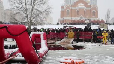 UKRAINE, KIEV, JANUARY 19, 2018: Sviato-Pokrovskiy Katedrali yakınlarındaki Dnieper Nehri kıyısında insanlar. Geleneksel kış, Kutsal Epifani Günü kutlamalarında soğuk suda yüzer. Buzda kırmızı cankurtaran salı