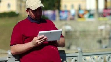 İşadamı tablet bilgisayarla çalışıyor. Adam tablet bilgisayar kullanıyor, tabletini elinde tutuyor.