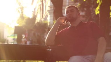 Adam bankta oturur ve güneş ışığında akıllı telefondan konuşur. İşadamı kürsüde oturuyor ve akıllı telefon aracılığıyla iletişim kuruyor.