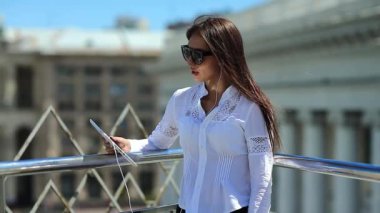 İş kadını tablet bilgisayarla iletişim kuruyor. Elinde tablet bilgisayarla güneş gözlüklü çekici bir kız Skype ya da görüntülü sohbet yoluyla iletişim kuruyor.