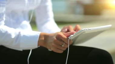 Kız kapalı çekimde tablet bilgisayar kullanıyor. Fransız manikürlü kadın elleri tablet bilgisayarı, arka planda güzel bir güneş tutuyor.
