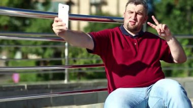 Kırmızı gömlekli adam selfie yapıyor. Adam akıllı telefonuyla fotoğraf çekiyor.