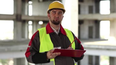 İnşaat alanındaki ustabaşı not alıyor. İnşaat alanında denetleyici personel. Proje alanında sarı şapkalı bir müfettiş. Mühendislik denetimi, inşaatçı notlar yazar