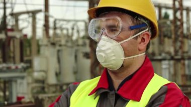 Gaz maskesi, gözlük ve elektrik santralinde güç mühendisliği uzmanı. Solunum cihazı ve gözlüklü işçiler elektrik santralinde ileriye bakıyor