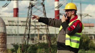 Elektrik santralinde taşınabilir radyo vericisi olan bir fabrika işçisi. Isı santrali enerji mühendisliği uzmanı radyo istasyonu aracılığıyla iletişim kuruyor.