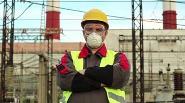 Elektrik santralindeki solunum cihazındaki işçi kameraya bakıyor. Gaz maskesi, gözlük ve ısı santralinde güç mühendisliği uzmanı.