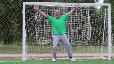 Kaleci futbol sahasında futbol kapısını koruyor. Futbol kapısında aktif yaşlı bir atlet. Son sınıf öğrencisi futbol kalesinde duruyor. Fiziksel aktivite kalori yakmaya yardımcı olur.